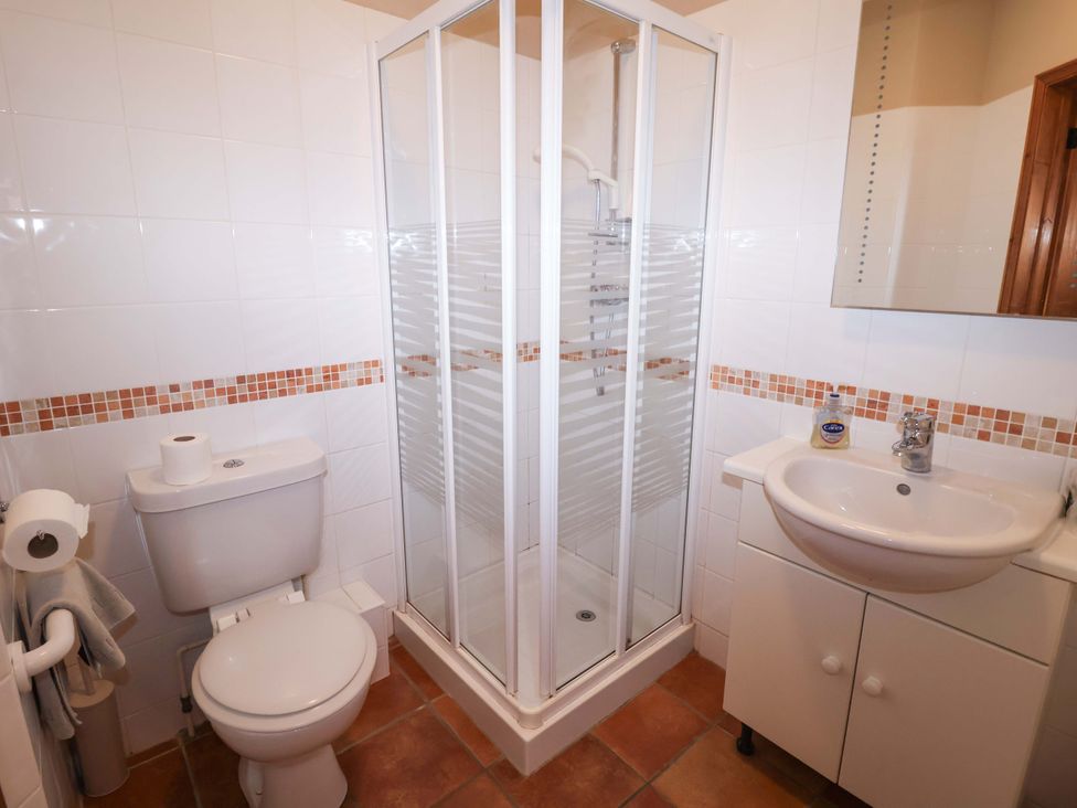 A bathroom with a shower, toilet, and sink at Coachman's Cottage in Ipswich