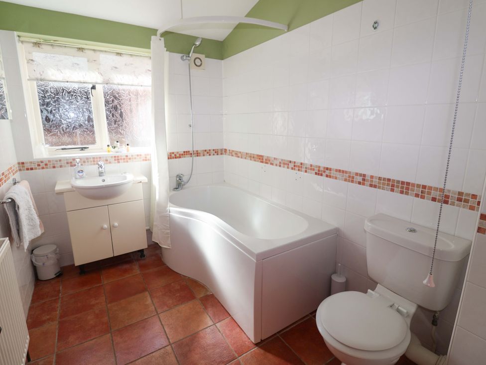 A bathroom with a bathtub and sink at Coachman's Cottage Ipswich