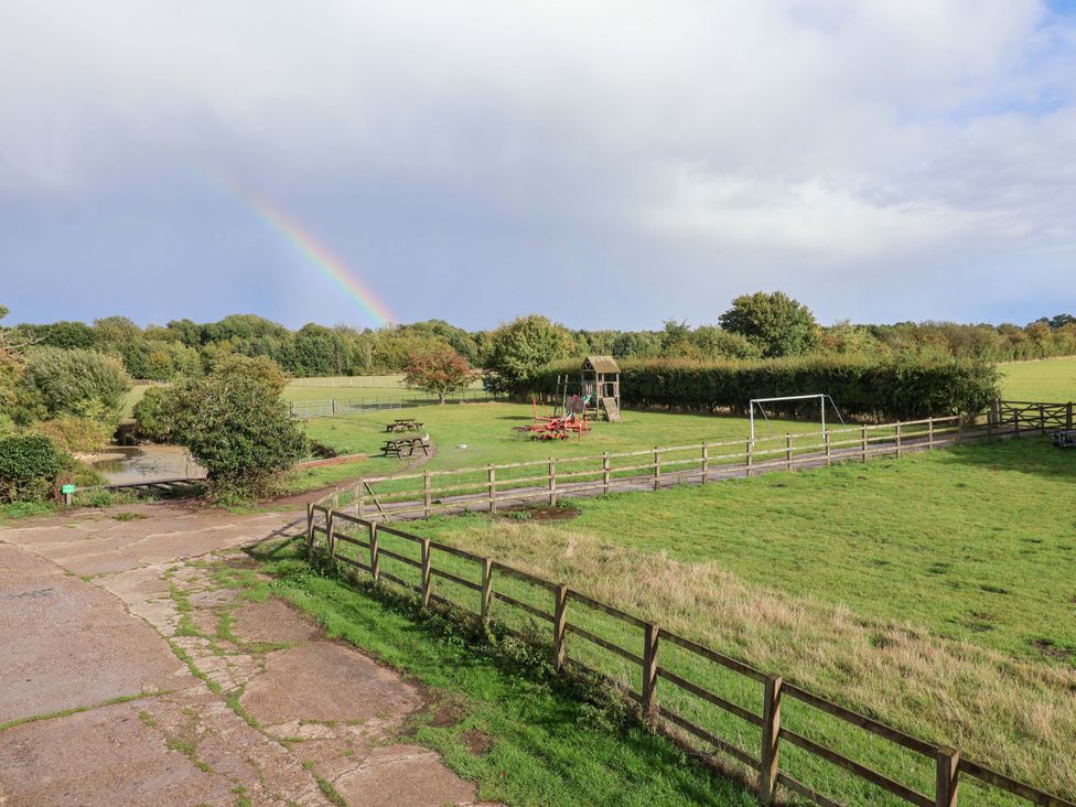 A field with a playground and picnic table at Coachman's Cottage in Ipswich