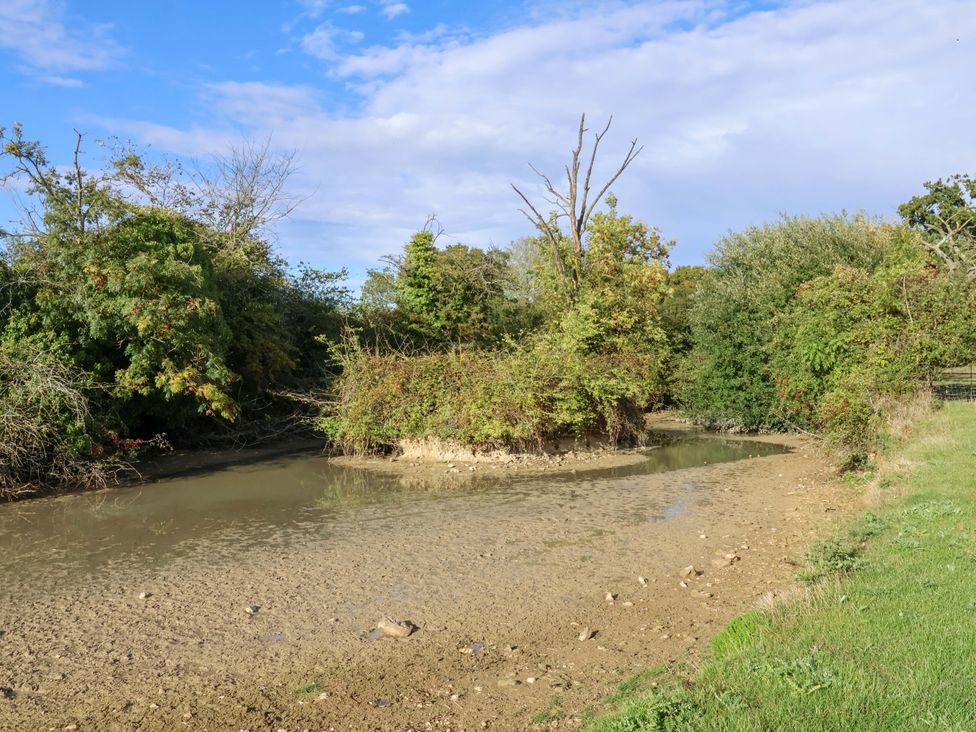 A natural scene with a riverbank and trees at Coachman's Cottage Ipswich