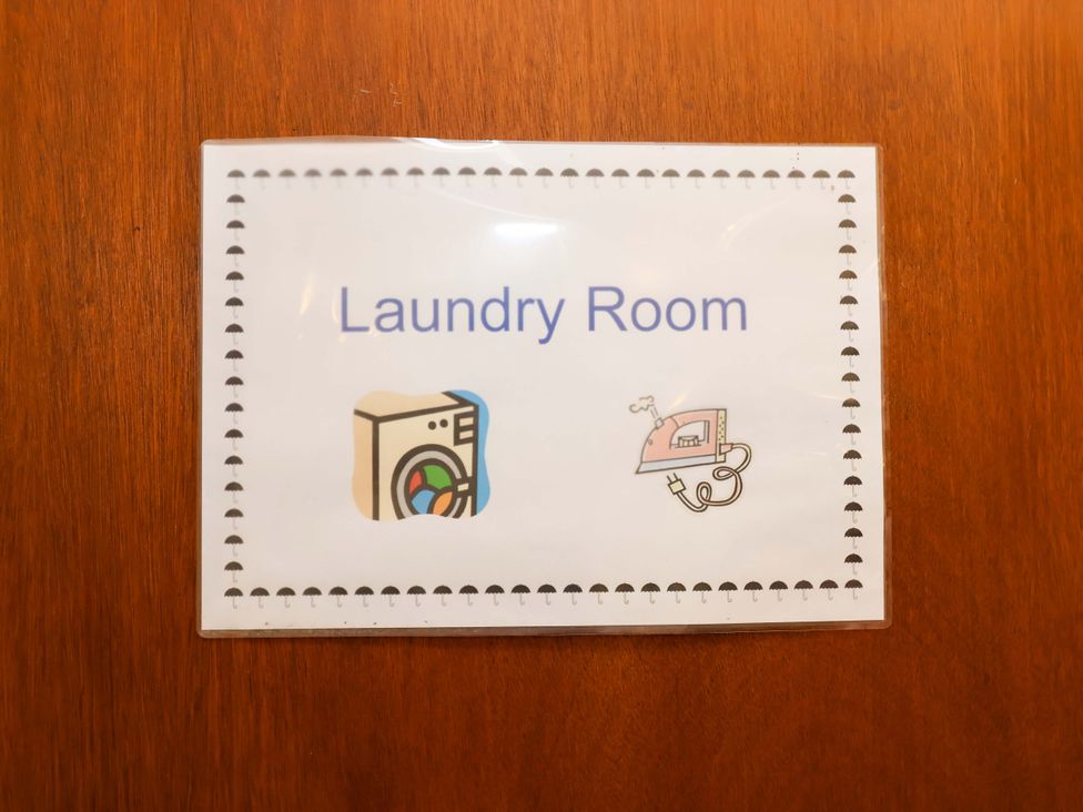 A sign indicating Laundry Room with icons at Coachman's Cottage Ipswich