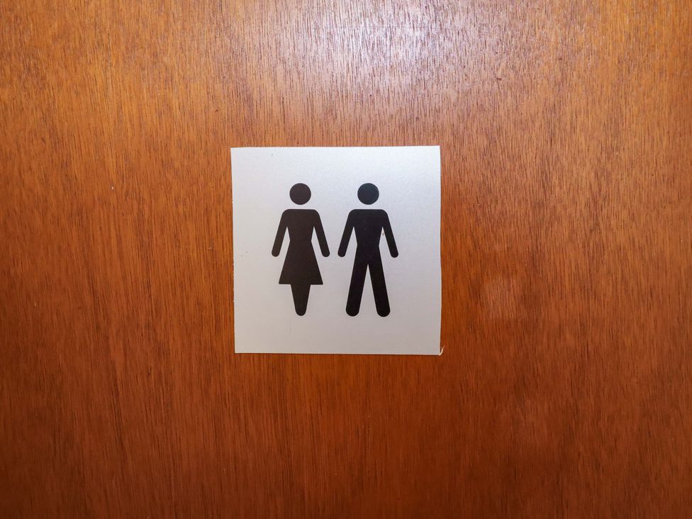 A bathroom door sign with male and female symbols at Coachman's Cottage Ipswich