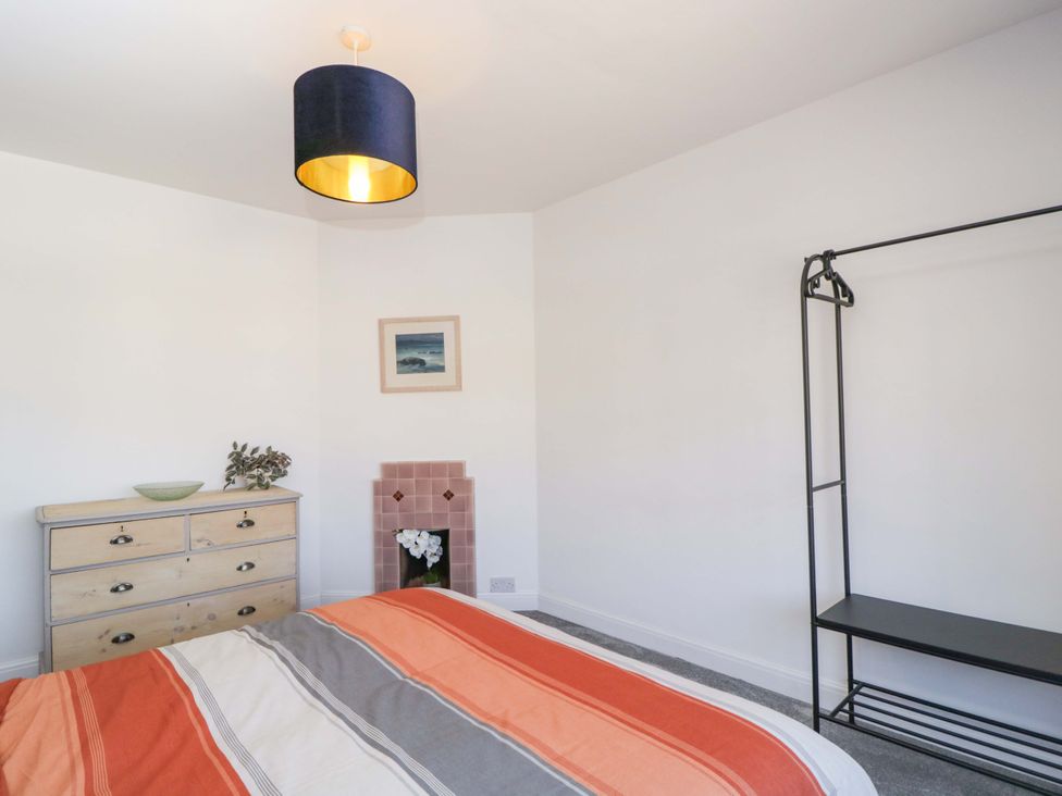 A bedroom with a bed, dresser, and hanging rack at 6 Newbridge Gardens Bath