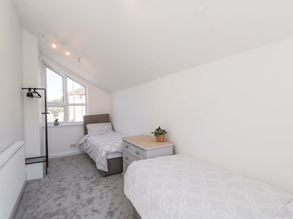A bedroom with two beds and a bedside table at 6 Newbridge Gardens in Bath