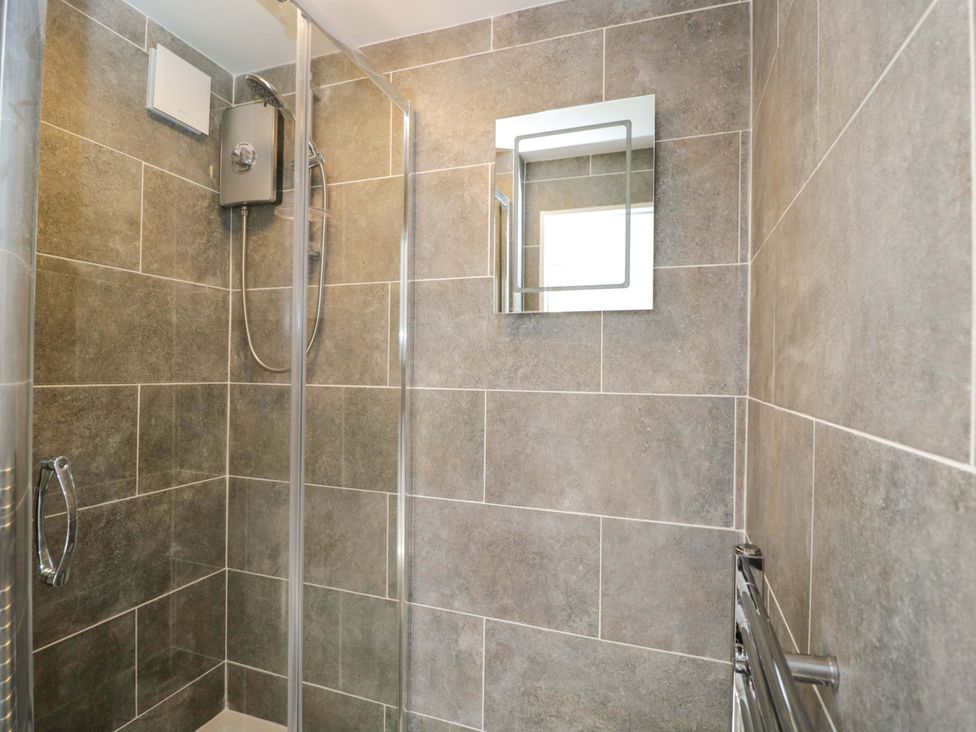 A shower with tiles and a mirror at 6 Newbridge Gardens Bath