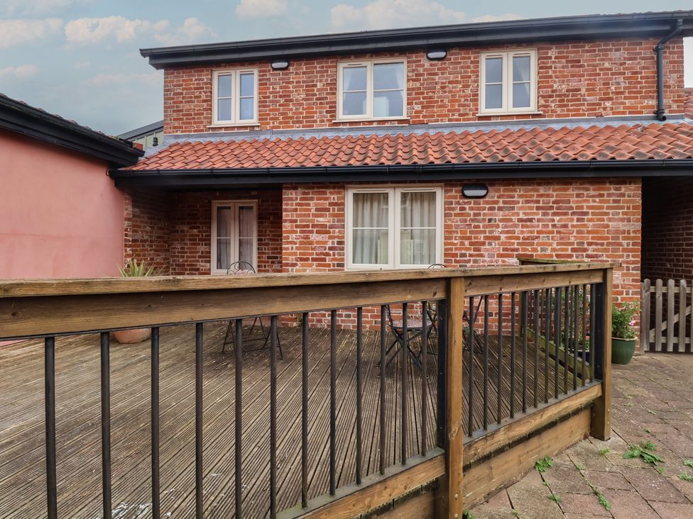 An outdoor area with a wooden deck and a two-story brick building at Blacksmith's Cottage Ipswich