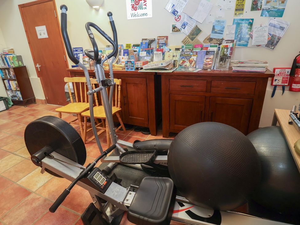 A gym area with exercise equipment and brochures at Blacksmith's Cottage in Ipswich