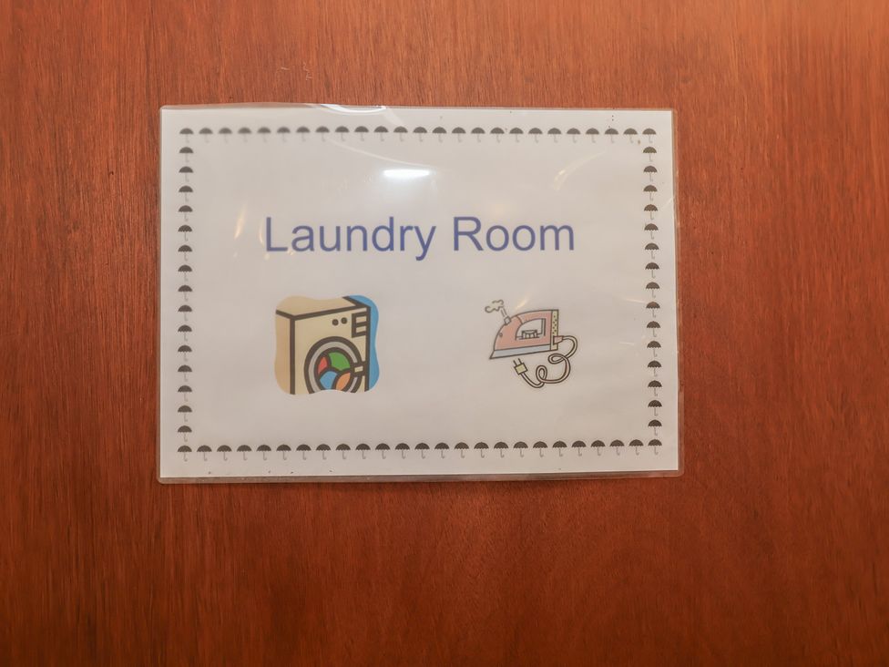 A sign indicating Laundry Room with icons at Wheelwright's Cottage in Ipswich