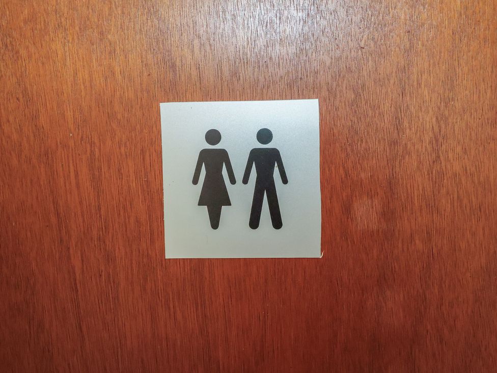 A restroom sign with male and female icons at Wheelwright's Cottage, Ipswich