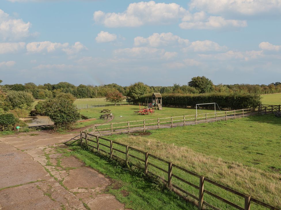 An outdoor area with a playground and picnic table at Wheelwright's Cottage in Ipswich