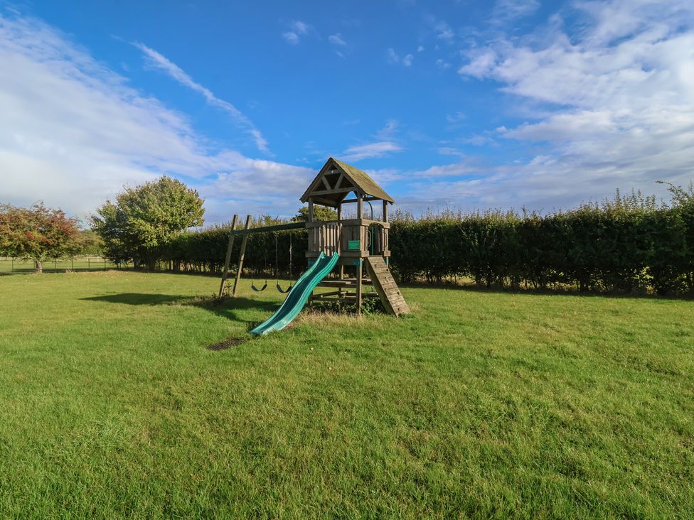 A playground structure with slide and swings at Wheelwright's Cottage in Ipswich