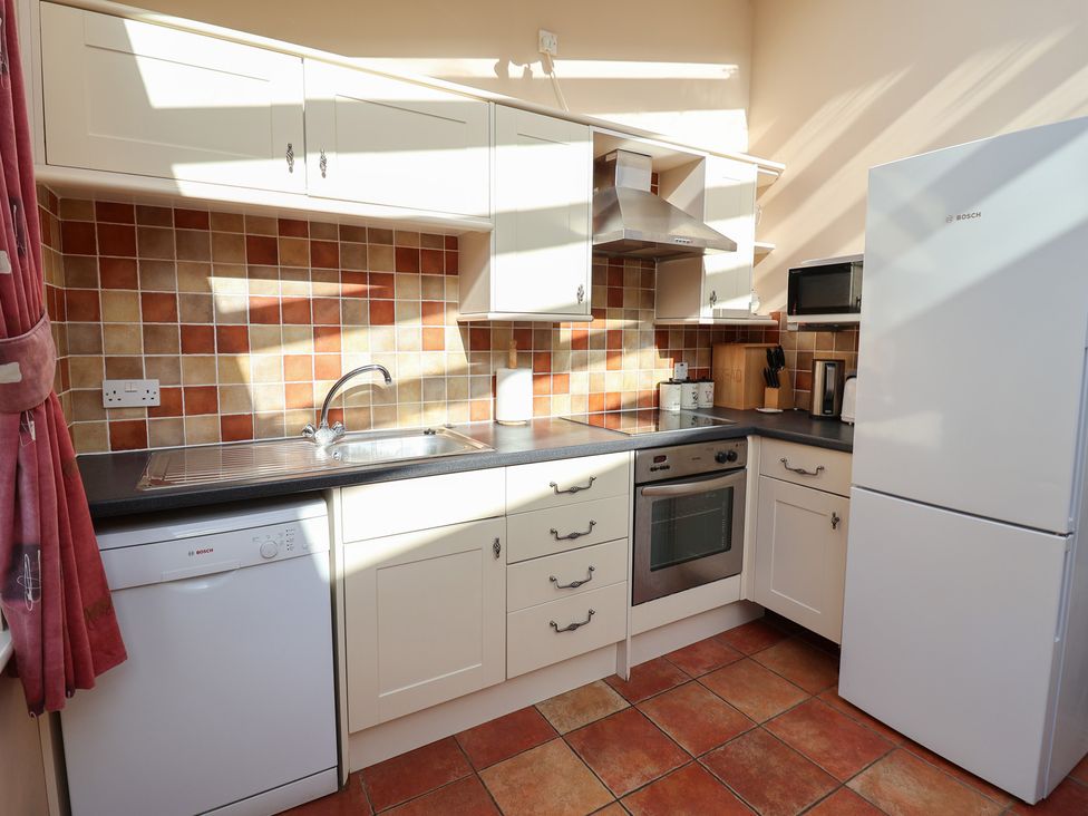 A kitchen with a sink, dishwasher, oven, and refrigerator at Wheelwright's Cottage in Ipswich