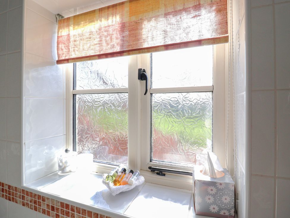 A bathroom window with shampoo bottles and toiletries at Wheelwright's Cottage in Ipswich