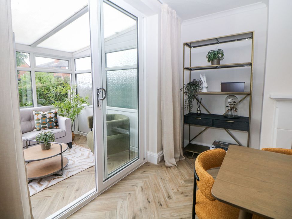 A conservatory with a sofa, coffee table, and shelves at 37 Berry Hill Lane in Mansfield