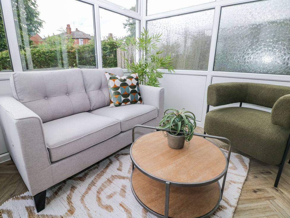 A conservatory with a sofa, armchair, coffee table, and plant at 37 Berry Hill Lane, Mansfield