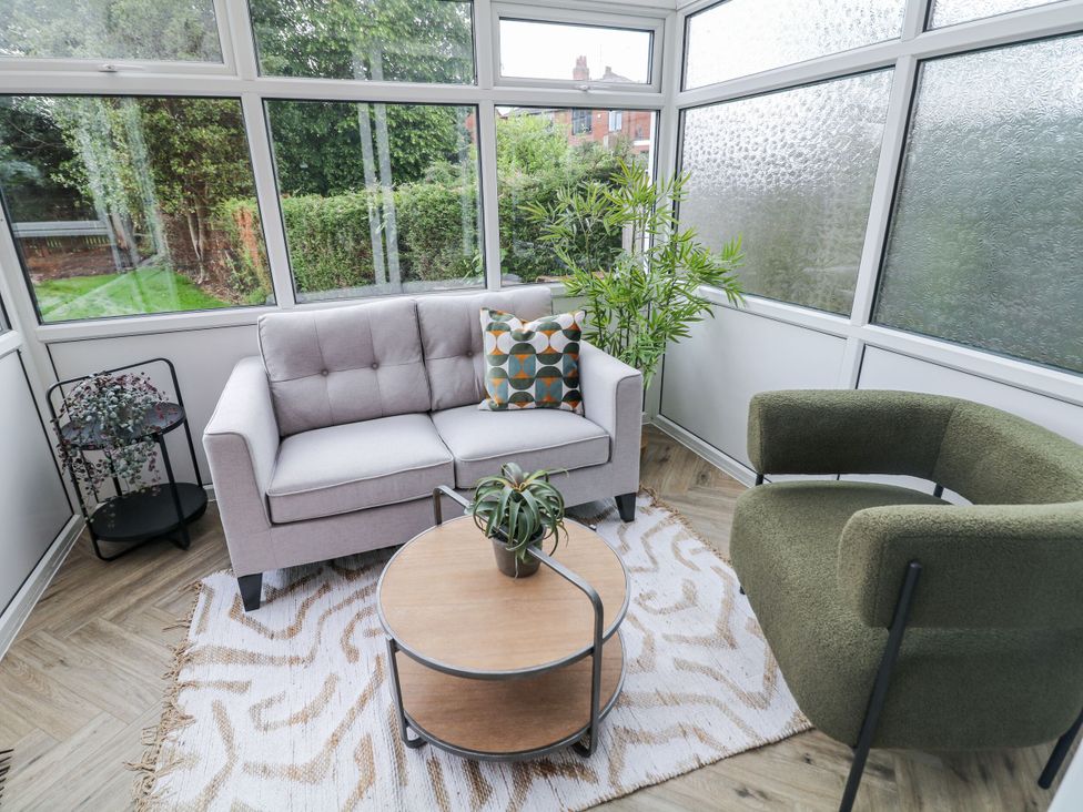 A conservatory with a sofa and armchair at 37 Berry Hill Lane Mansfield