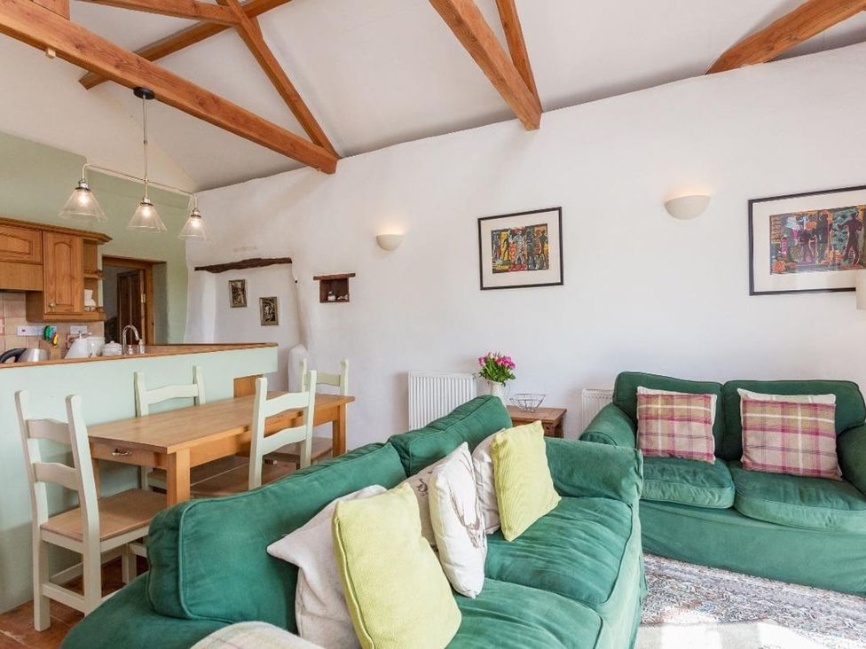 A living room with a sofa and dining area at Billy's Barn in Bradworthy