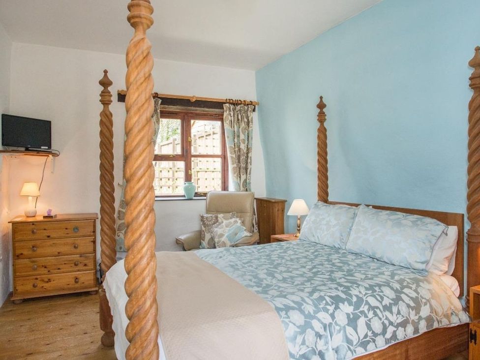 A bedroom featuring a four-poster bed and a wooden dresser at Billy's Barn in Bradworthy