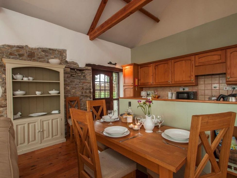 A kitchen with a wooden dining table and chairs at Billy's Barn in Bradworthy
