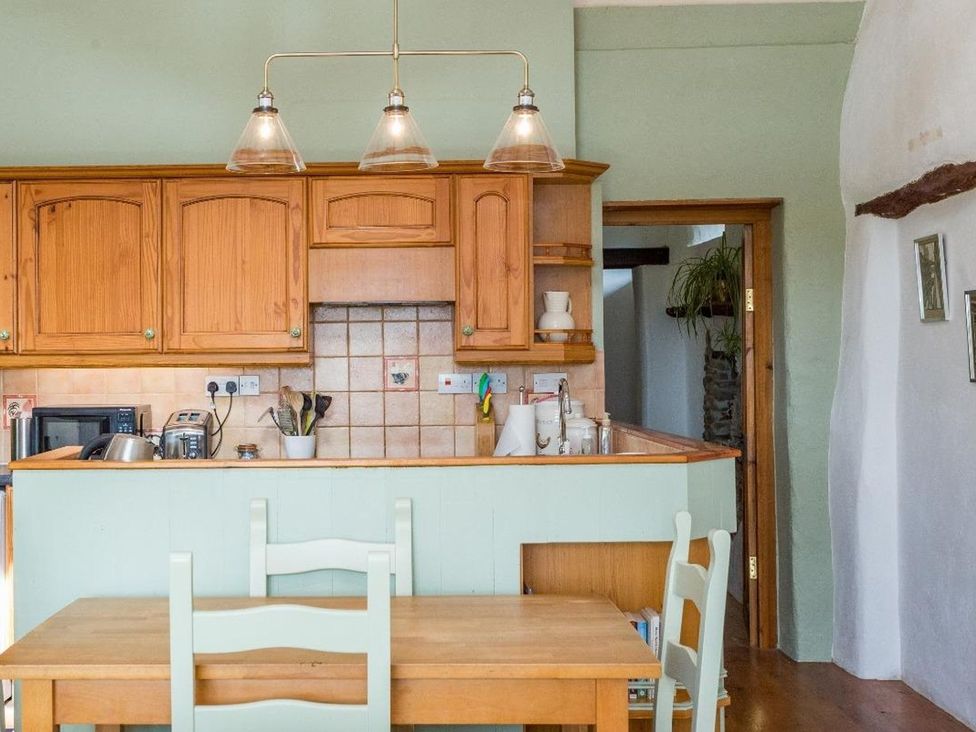 A kitchen with wooden cabinets and table at Billy's Barn in Bradworthy