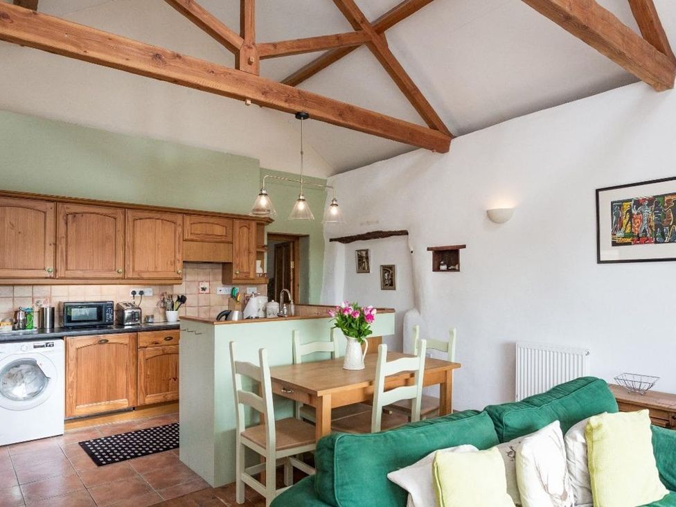 A kitchen with a dining area and washing machine at Billy's Barn in Bradworthy