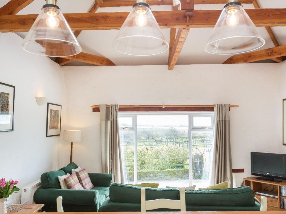 A living room with a green sofa and television at Billy's Barn in Bradworthy