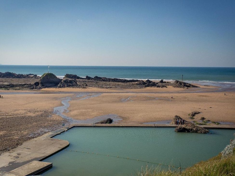 A beach scene with rock formations and a jetty near the sea at Billy's Barn in Bradworthy