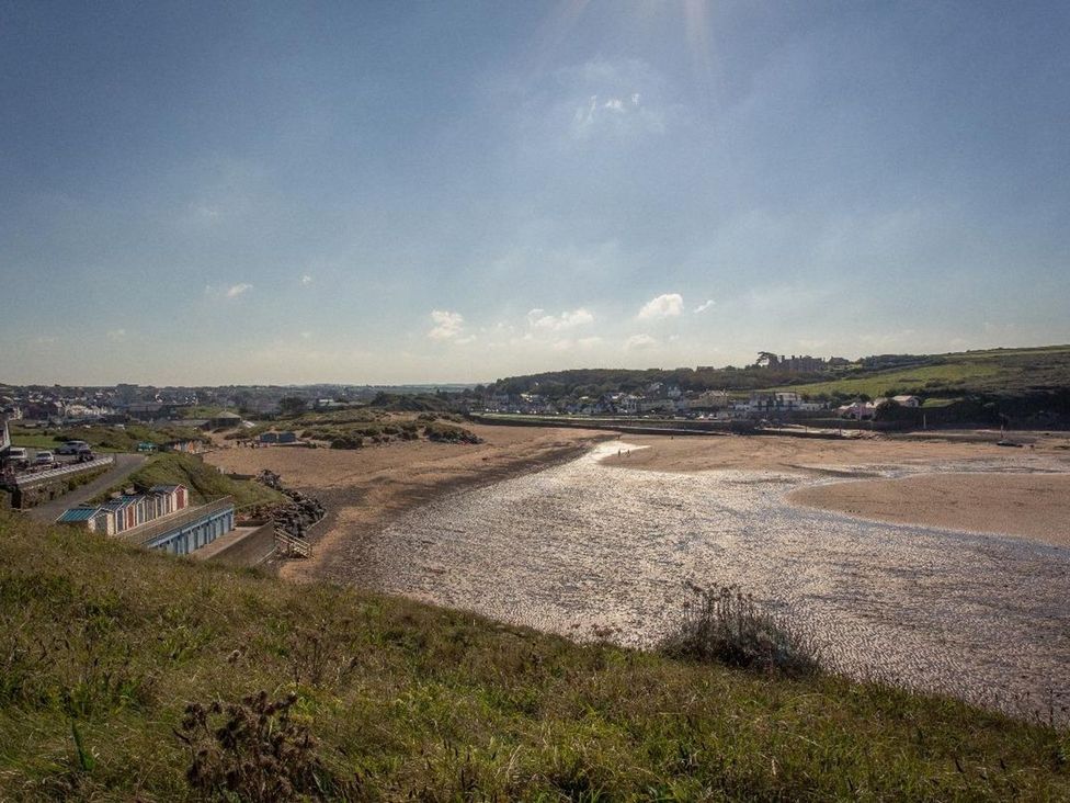 A beach view with sand and water and beach huts at Billy's Barn in Bradworthy