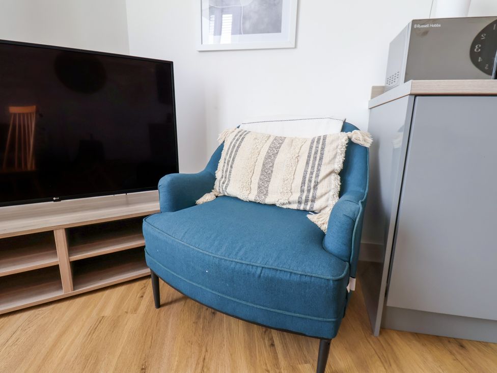 A living room with a chair and television at Apartment 3 (2 bed) Redcar