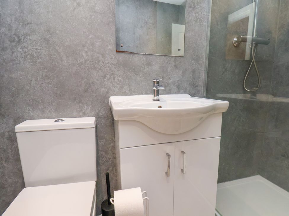 A bathroom with a toilet, sink, shower and mirror at Apartment 3 ( 2 bed ) Redcar
