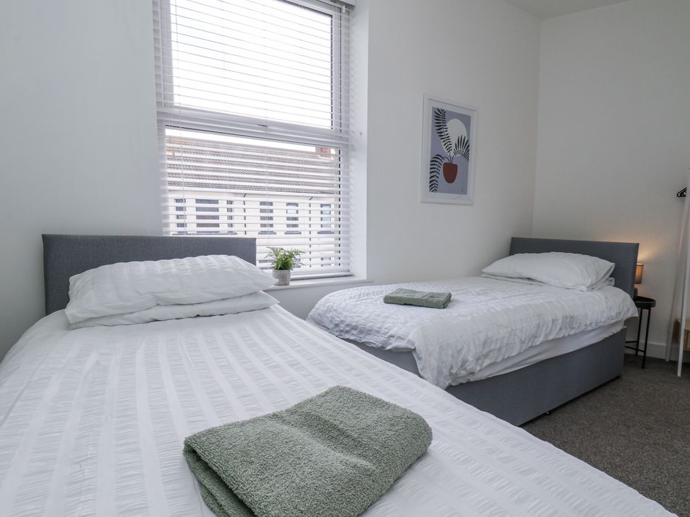 A bedroom with two beds and a plant by a window at Glenholme Apartment 3 Redcar