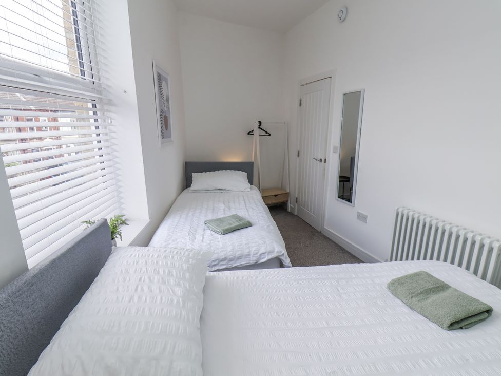 A bedroom with two beds and a mirror at Glenholme Apartment 3 in Redcar