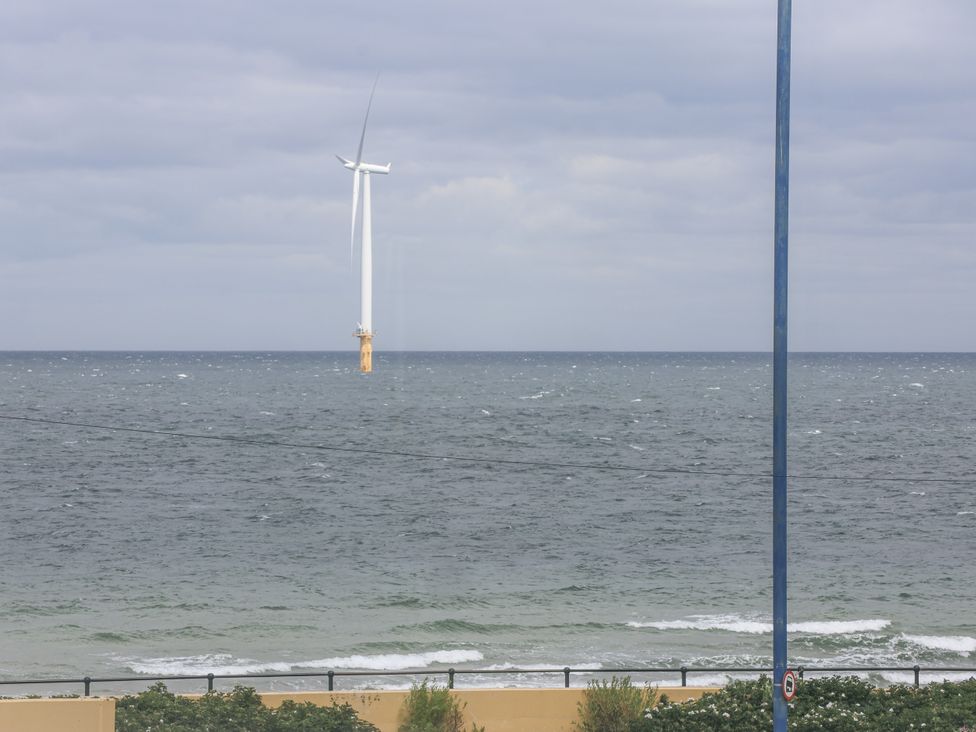A wind turbine in the ocean with waves at Glenholme Apartment 3 Redcar