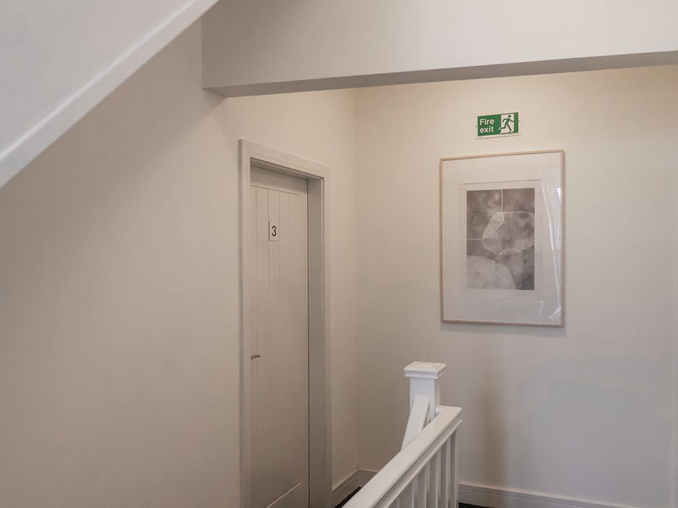 A hallway with a door labeled 3 and a fire exit sign at Glenholme Apartment 3 Redcar