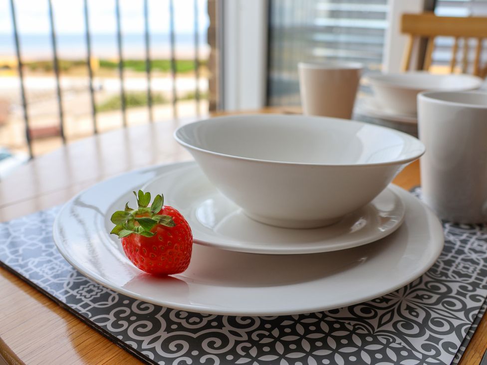 A dining table set with plates and a strawberry at Apartment 4 (1 bed) Redcar