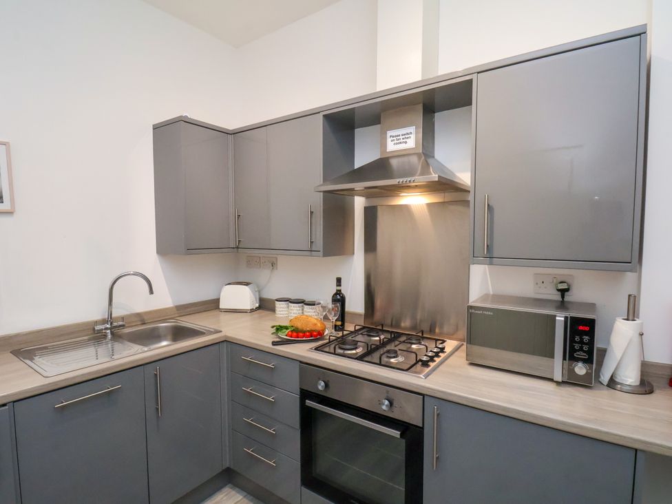 A kitchen with gray cabinets and appliances at Apartment 4 (1 bed) Redcar