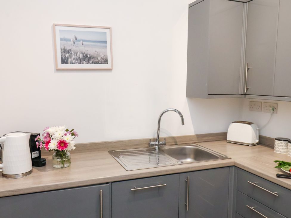 A kitchen with a sink, kettle, and framed picture at Apartment 4 ( 1 bed ) Redcar