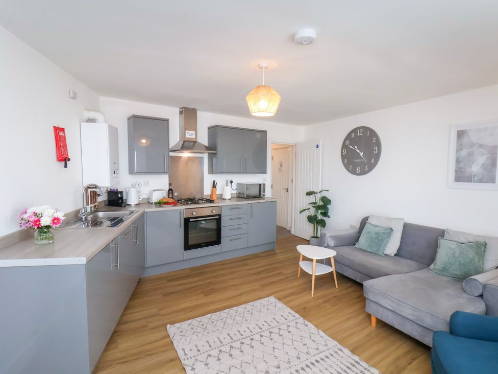 A living room with a kitchen area and a clock at Apartment 5 ( 1 bed ) Redcar