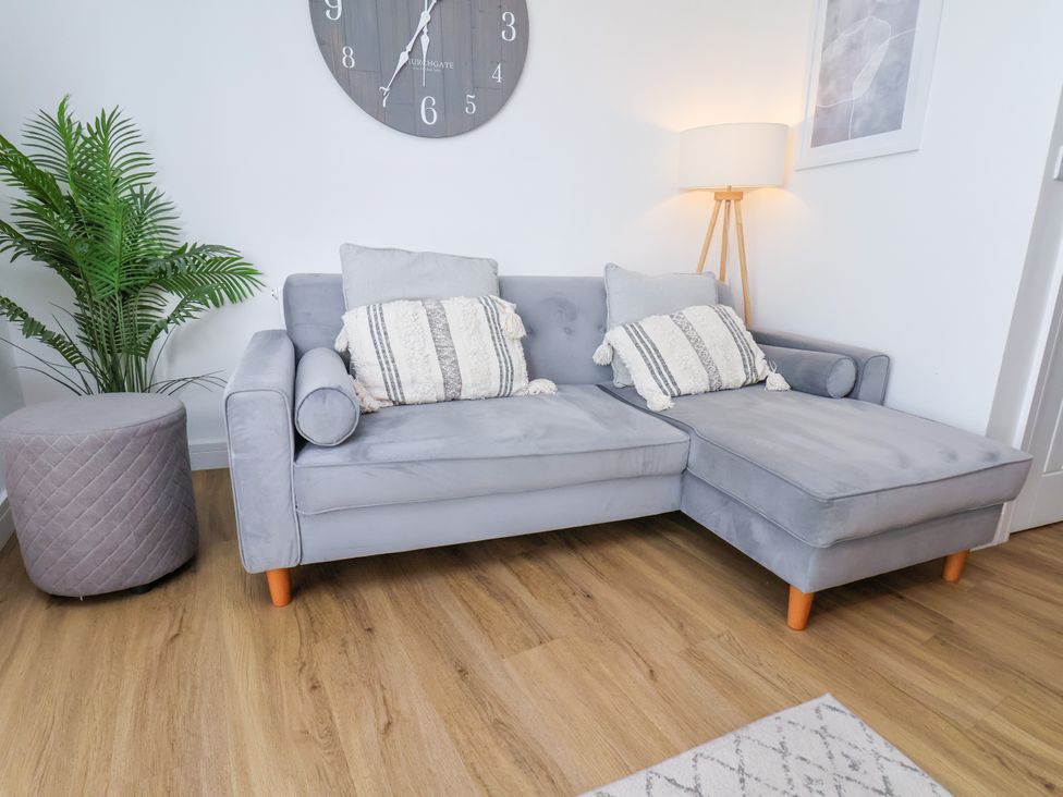 A living room with a grey sofa and a potted plant at Apartment 6 (1 bed) Redcar
