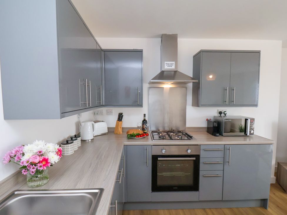 A kitchen with cabinets, stove, sink, and microwave at Apartment 6 (1 bed) in Redcar