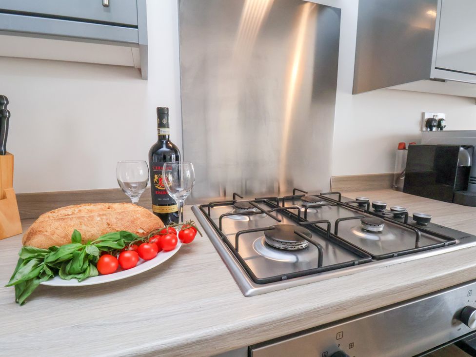A kitchen with a stove, wine glasses, tomatoes, bread, and a wine bottle at Apartment 6 ( 1 bed ) Redcar