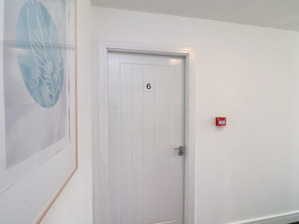 A corridor with a door number 6 and wall art at Apartment 6 (1 bed) in Redcar