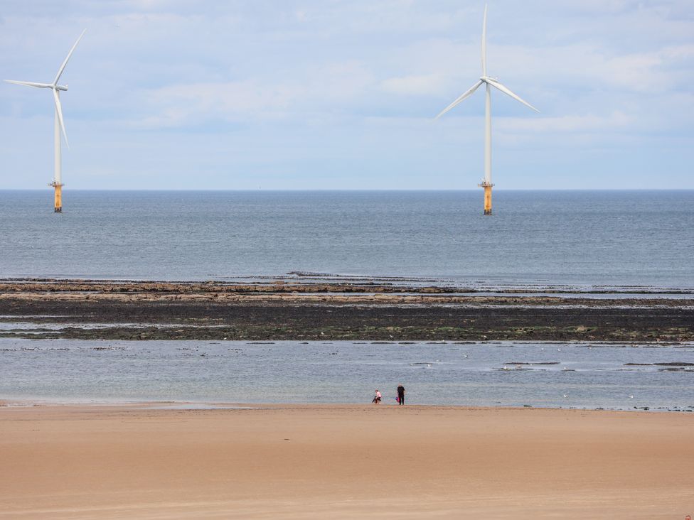 A beach with wind turbines in the background at Apartment 6 ( 1 bed ) Redcar