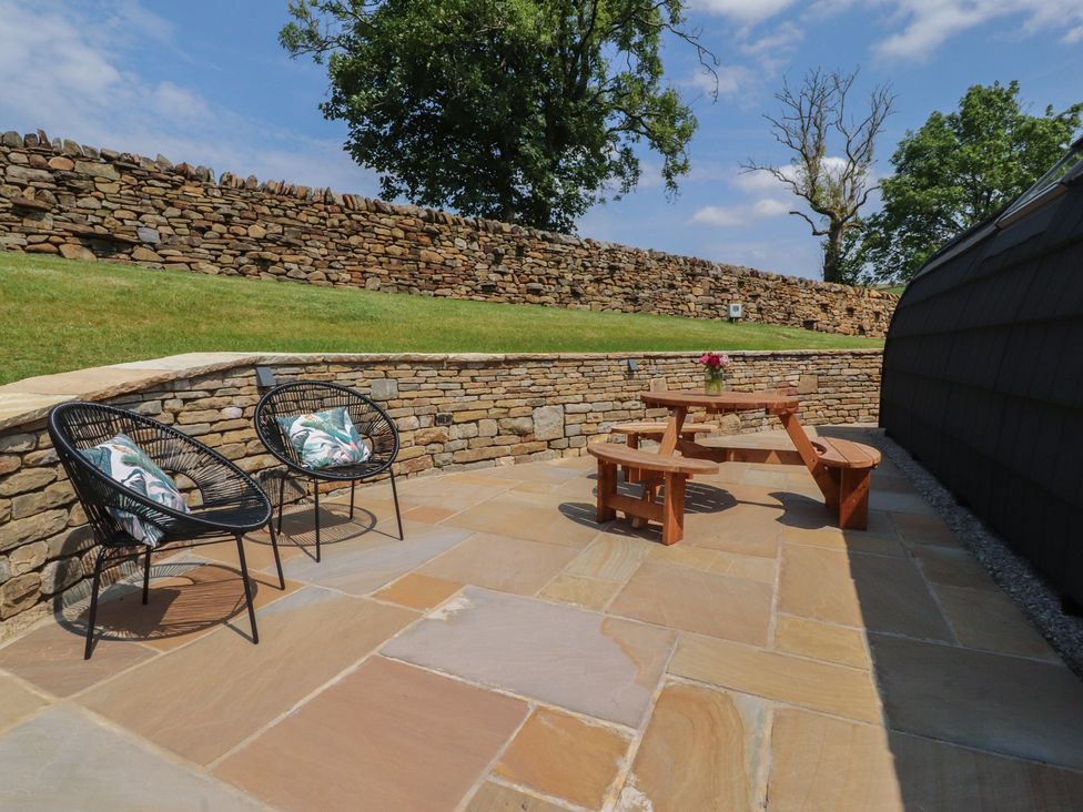 An outdoor seating area with a wooden table and stone wall at Barley near Nelson