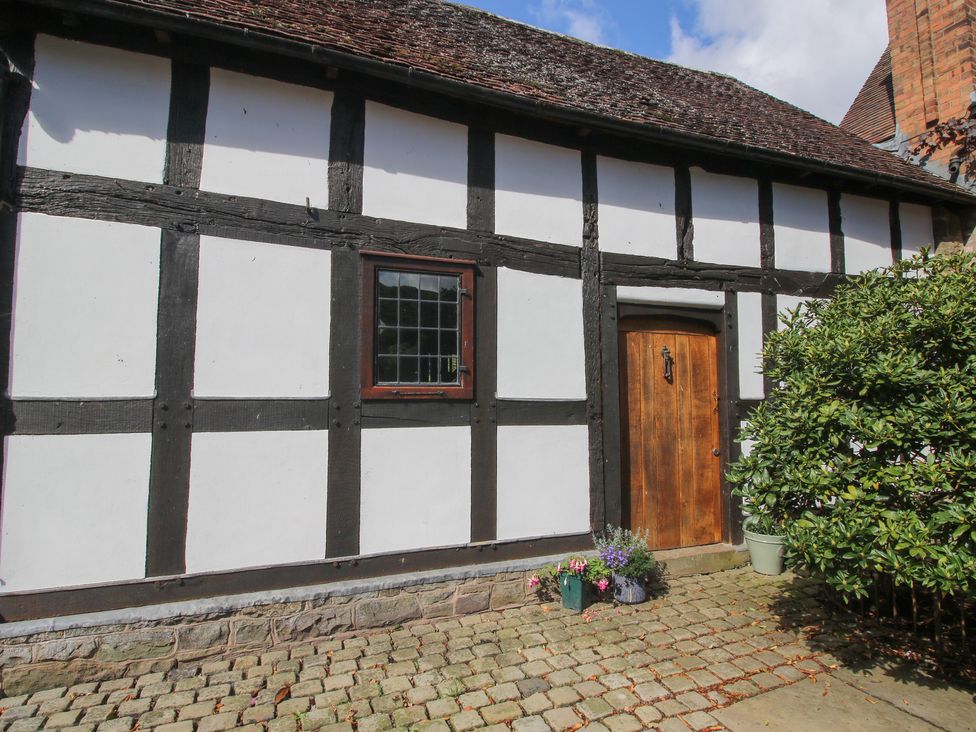 Exterior view of a house with wooden door and window at Courtyard Cottage in Little Stretton
