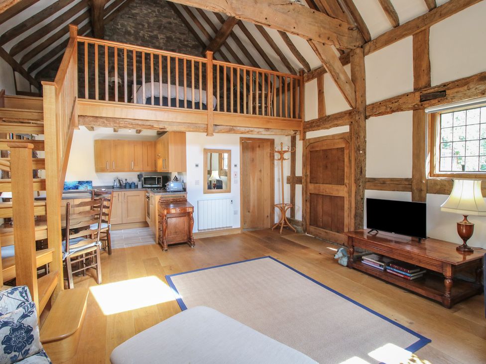 A living room with a kitchen and stairway at Courtyard Cottage in Little Stretton