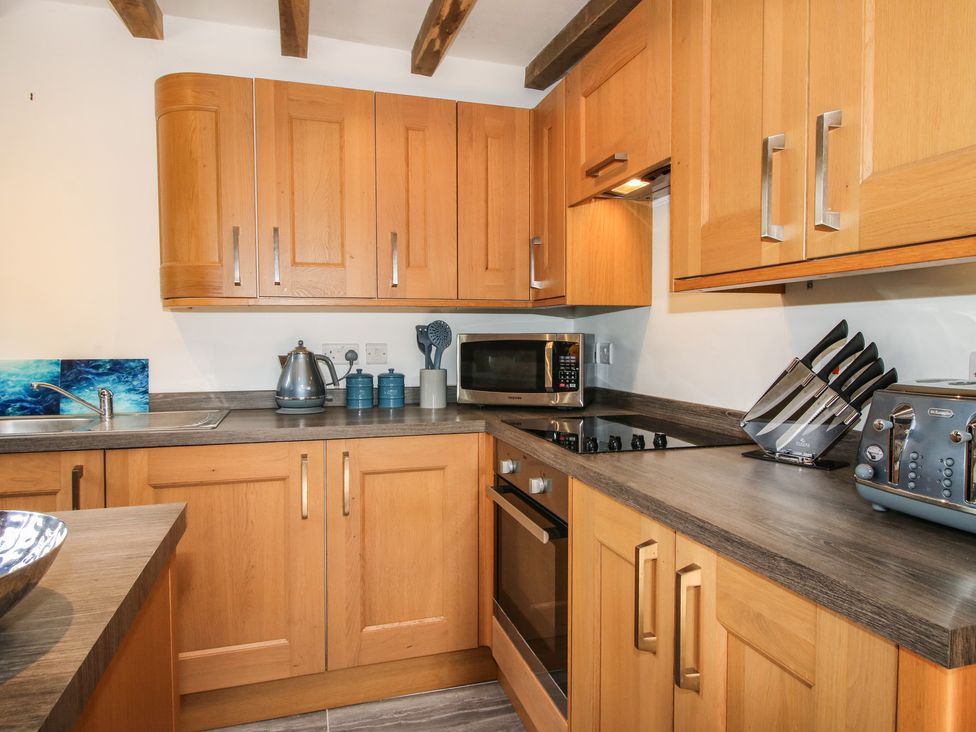 A kitchen with wooden cabinets and appliances at Courtyard Cottage in Little Stretton