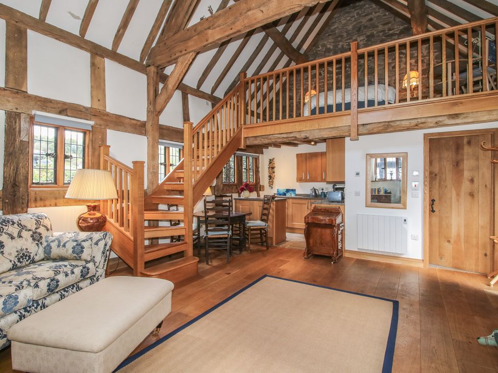 A living room with a staircase and kitchen at Courtyard Cottage in Little Stretton