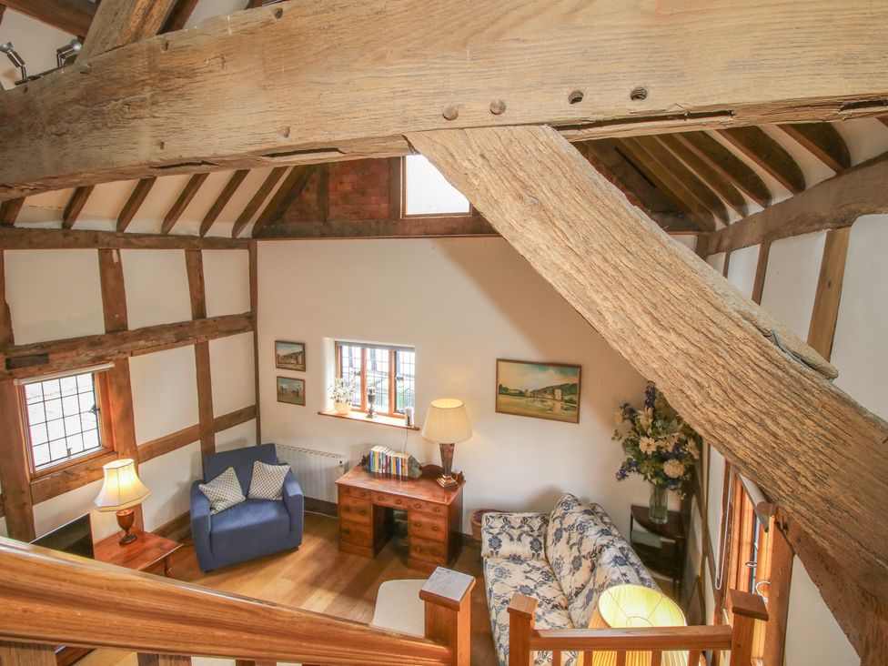 A living room with a sofa and desk at Courtyard Cottage in Little Stretton