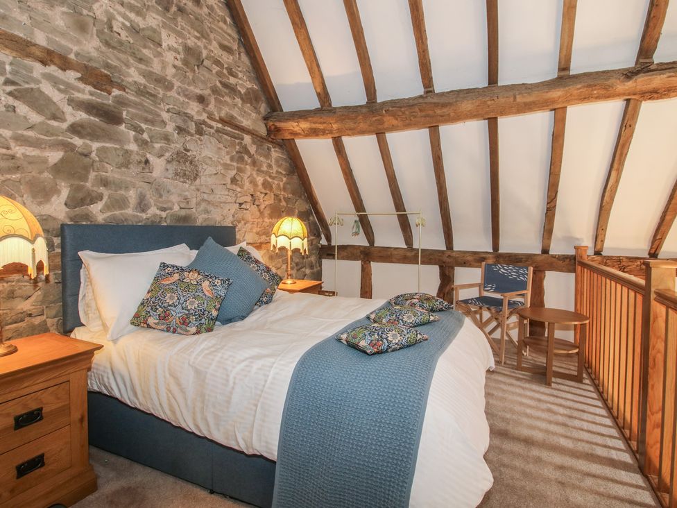 A bedroom with a bed and bedside tables at Courtyard Cottage in Little Stretton